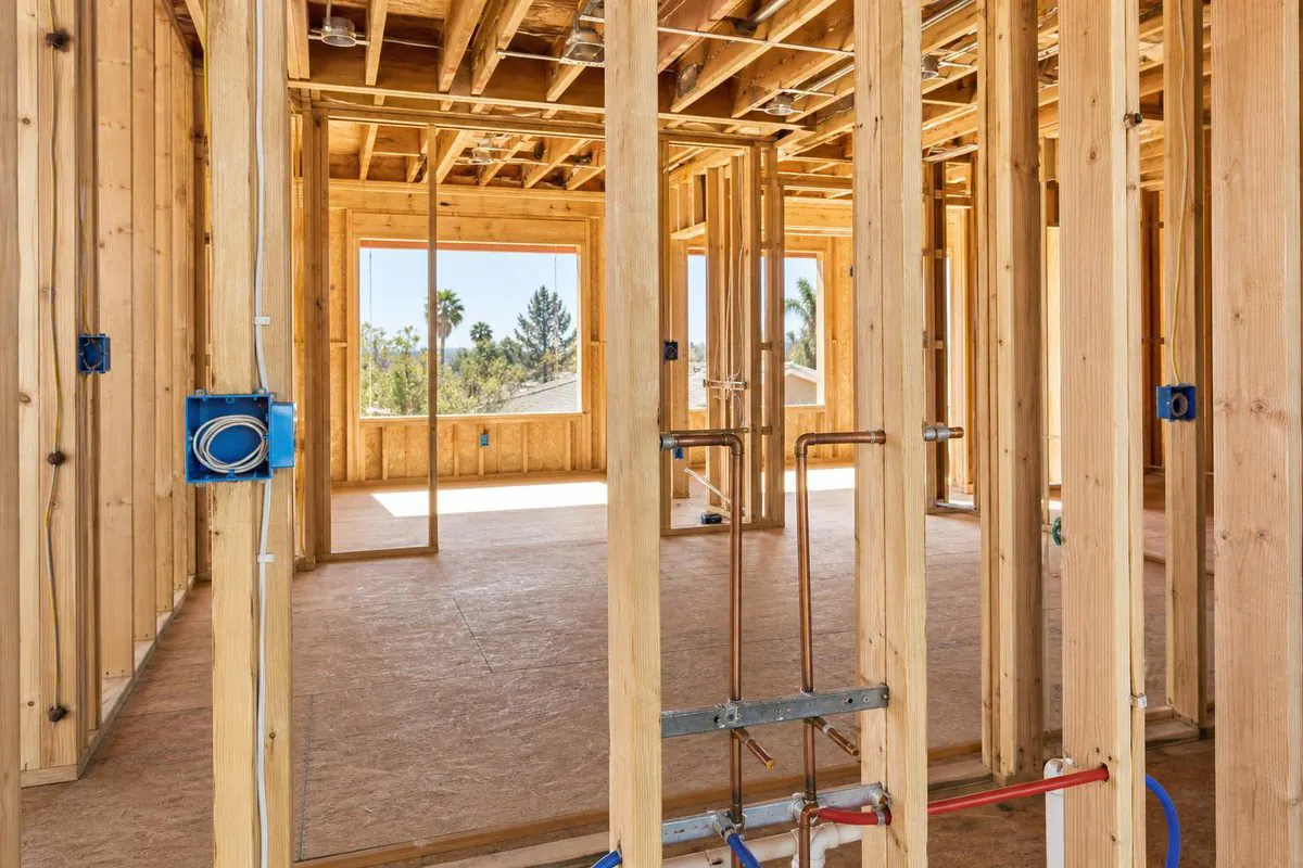 An unfinished interior with exposed studs, electrical boxes and rough plumbing